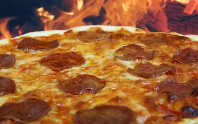 Pyszna pepperoni pizza z ciągnącym się serem, pieczona w ogniu.