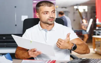 Mężczyzna z dokumentem i kciukiem w górze, pokazujący jak znaleźć kod PKD.