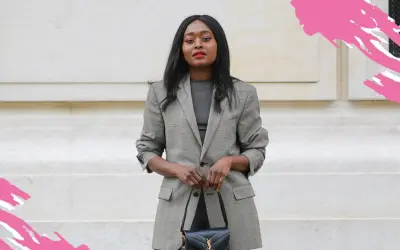 Eine Frau im karierten Blazer und schwarzer Tasche zeigt, was ist business casual: schick und doch entspannt.
