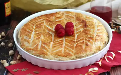 Une délicieuse galette pistache framboise dorée, décorée de fruits rouges frais, prête à être dégustée.
