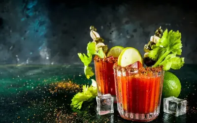 Dwa drinki Krwawa Mary z łodygami selera, limonką i piklami. Idealny przepis na brunch.