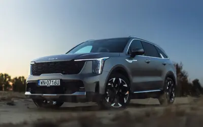 Szary SUV Kia Sorento na tle pustynnego krajobrazu o zachodzie słońca.