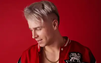 Młody mężczyzna z blond włosami i złotym łańcuchem na szyi, w czerwonej kurtce. Ile lat ma Skolim?