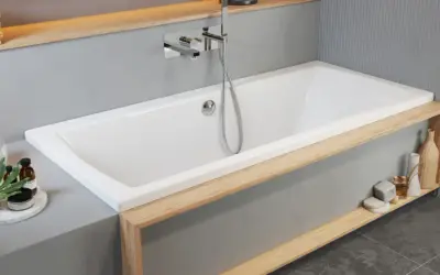 Moderne Badewanne einbauen: Weiße Wanne mit Holzakzenten, Armatur und Handbrause. Dekorative Elemente wie Lampen und Flaschen schmücken die Ablage.
