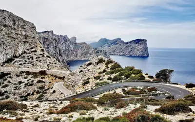 Carretera sinuosa en acantilados rocosos con vistas al mar azul. Un viaje en coche por un paisaje espectacular.
