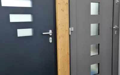 Dwie nowoczesne drzwi wejściowe, ciemnoszare i szare, z przeszkleniami. Dowiedz się, jak uszczelnić drzwi wejściowe, by zapewnić komfort.