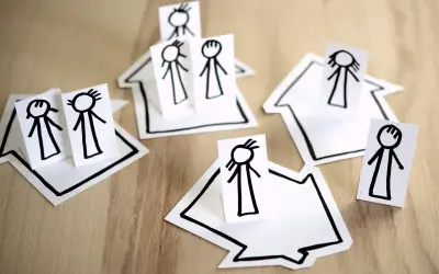 Proste rysunki postaci na domkach symbolizują inkluzję i wspólnotę.