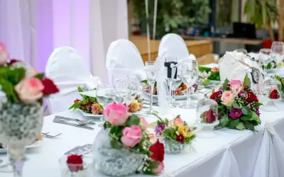 Elegancko nakryty stół weselny z bukietami róż i goździków. Idealne pomysły na wesele, pełne romantyzmu i stylu.