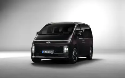 Ciemny Hyundai Staria z charakterystycznym pasem świateł LED na przodzie, gotowy na rodzinne podróże.