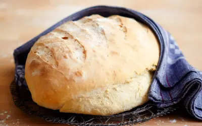 Frisch gebackenes Brot, das nach dem **Brot selber backen** auf einem Gitter abkühlt. Ein blau-weißes Tuch umhüllt es.