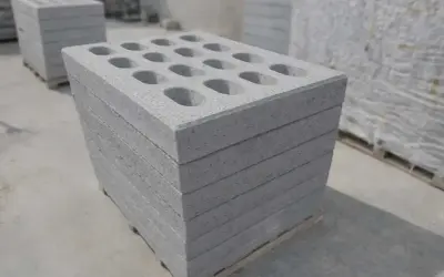 Stos betonowych pustaków z otworami na palecie.