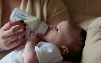 A baby drinks from a bottle. Concerns exist about does bottle feeding affect teeth alignment, but this image focuses on a moment of nourishment.