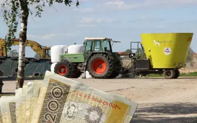 Zielony traktor z przyczepą paszową na tle pola i sterty bel. W tle koparka. Na pierwszym planie polskie banknoty 200 zł. Eudr co to? Inwestycja w rolnictwo.