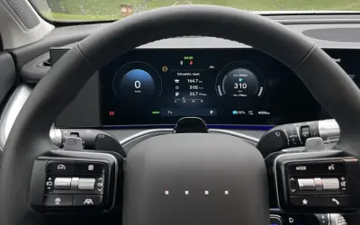 Wnętrze samochodu elektrycznego marki Hyundai. Na ekranie widoczny zasięg 310 km, zużycie energii i inne dane.