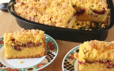 Pyszne ciasto z mąki kukurydzianej z soczystymi śliwkami i kruszonką. Dwa kawałki na talerzykach, reszta w formie.