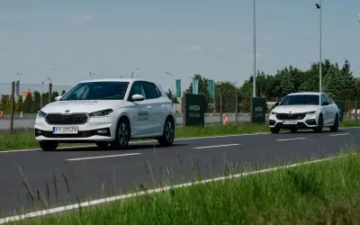 Białe Skody na torze szkoleniowym, jedna próbuje wyprzedzanie drugiej.