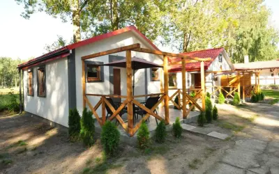 Urocze domki letniskowe "Albatros" w Łebie, z drewnianymi tarasami i zielenią wokół, zapraszają na wypoczynek.