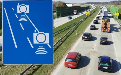 Niebieski znak z białymi ikonami kamer i falami, obok autostrady z ruchem samochodowym.