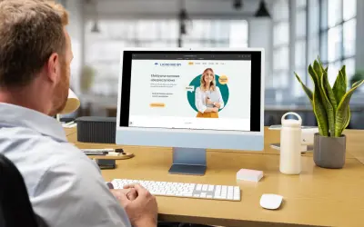 Mężczyzna pracuje przy komputerze, na ekranie którego widoczna jest strona internetowa agencji ubezpieczeniowej.