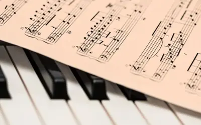 Partytura muzyczna z nutami, leżąca na klawiaturze fortepianu. Może to być utwór JS Bacha, gotowy do zagrania.