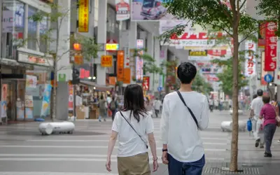 Para dowiedzieć się, jak rozmawiać z chłopakiem, obserwuj tę parę spacerującą po tętniącej życiem ulicy handlowej w Japonii, otoczonej neonami i sklepami.