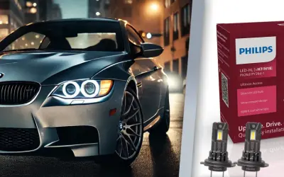 Srebrne auto z włączonymi światłami LED na tle miasta. Obok opakowanie żarówek Philips Ultinon Access, które jakie żarówki odmienią nocną jazdę.