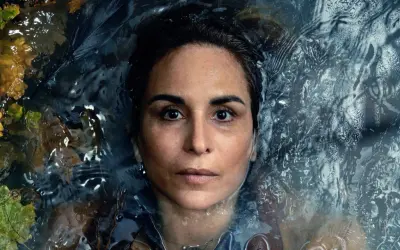En kvinna med intensiv blick flyter i mörkt vatten, omgiven av höstlöv. En scen från veronica serie.
