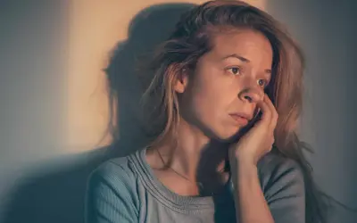 Une femme songeuse, le regard perdu, se demande : "suis je sous l'emprise d'un manipulateur test ?" Son visage exprime le doute et l'inquiétude.