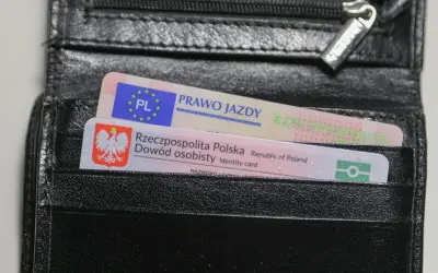 Czarny portfel z polskim dowodem osobistym i prawem jazdy. Na dokumencie prawa jazdy widnieje napis "PRAWO JAZDY", a na dowodzie "Rzeczpospolita Polska Dowód osobisty". Brak widocznych ograniczeń 71.