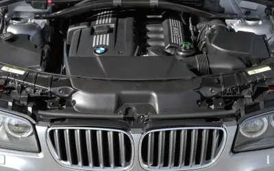 Silnik BMW X3 2005. Widok komory silnika z charakterystyczną atrapą chłodnicy i logo BMW.