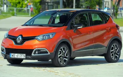 Pomarańczowy Renault Captur 2015 z czarnym dachem i pomarańczowymi akcentami, zaparkowany na placu.