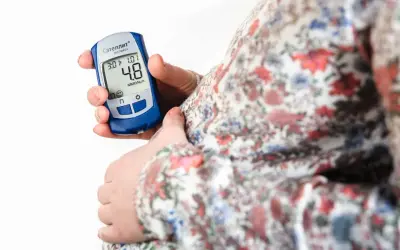 Gravid kvinna kontrollerar sitt blodsocker med en glukosmätare. En viktig del av att hantera graviditetsdiabetes.