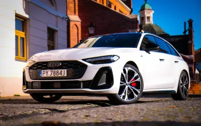 Białe Audi A5 2025 z czerwonymi zaciskami hamulcowymi na tle zabytkowej architektury.