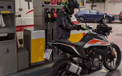 Motociclista repostando su moto 390 Adventure. La pregunta sobre qué gasolina usan las motos de 49cc es relevante para este tipo de vehículos.