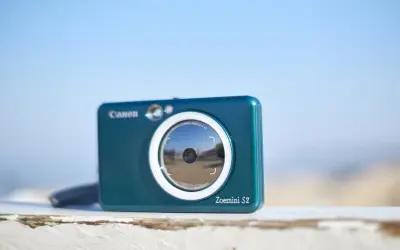 Niebieski aparat Canon Zoemini S2, idealny aparat na wakacje, gotowy do łapania wspomnień.