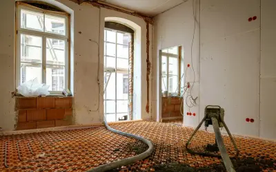 Installation d'un chauffage au sol ancienne génération, avec tuyaux orange et une machine de projection de chape.