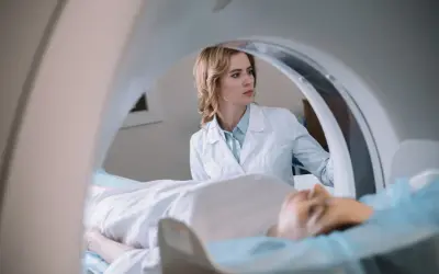 Lekarka nadzoruje badanie rezonans serca. Pacjent leży na stole aparatu MRI.