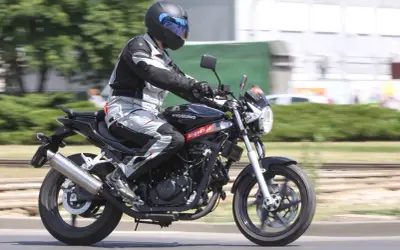 Motocyklista w pełnym stroju pędzi na czarnym Hyosung GT 125, ciesząc się jazdą.
