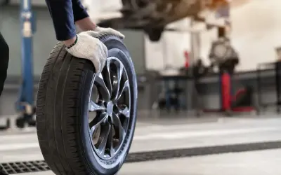 Mechanik w rękawiczkach trzyma oponę. Czy opony rowerowe do miasta z gładkim bieżnikiem zużywają się szybciej na kostce i asfalcie?