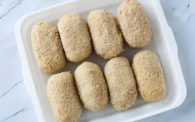 Ocho croquetas empanadas listas para cocinar en la airfryer.