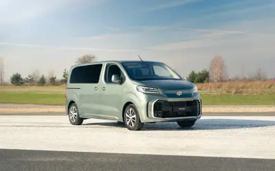 Nowy, zielony minivan Toyota Proace Verso na tle nieba i pól. Idealny na rodzinne wycieczki.