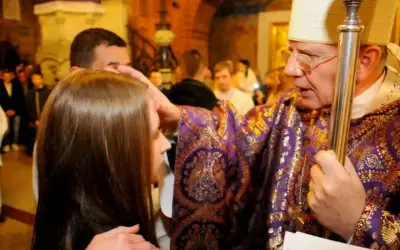 Biskup udziela sakramentu bierzmowania. Ceremonia trwa krótko, ale jest pełna duchowego znaczenia.