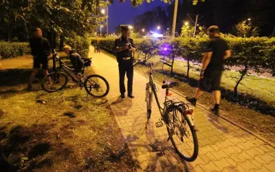 Policjant rozmawia z rowerzystą, który może stracić prawo jazdy. Nocna interwencja na ścieżce rowerowej.