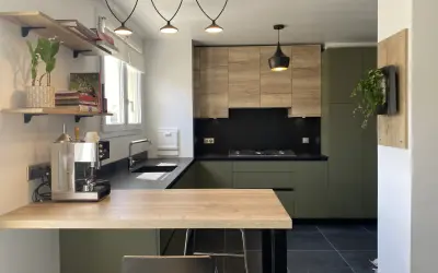 Cuisine moderne avec meubles vert olive, bois clair et plan de travail noir.