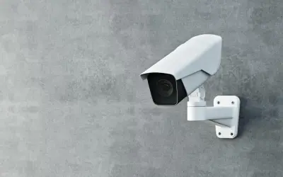Une caméra de surveillance blanche est fixée sur un mur de béton. Cette caméra sans internet assure une sécurité discrète.