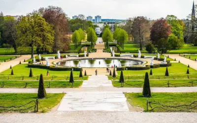 Ein prächtiger Park mit einem runden Teich, Statuen und gepflegten Rasenflächen. Ein ideales Motiv für Ausflugsziele Potsdam.