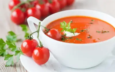 Aksamitna zupa pomidorowa z kleksem śmietany i gałązką pomidorków koktajlowych. Idealna na lekki posiłek, zupa pomidorowa kcal.