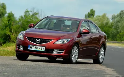 Czerwona Mazda 6 2.0 benzyna jedzie po drodze, za kierownicą siedzi mężczyzna.
