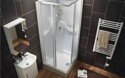Salle de bain moderne avec une cabine de douche aux dimensions compactes, un lavabo suspendu et un sèche-serviettes.