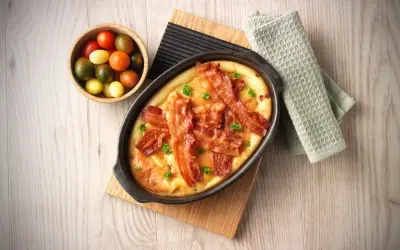 En härlig ugnspannkaka med knaprigt bacon och färska örter, serverad med en skål körsbärstomater.